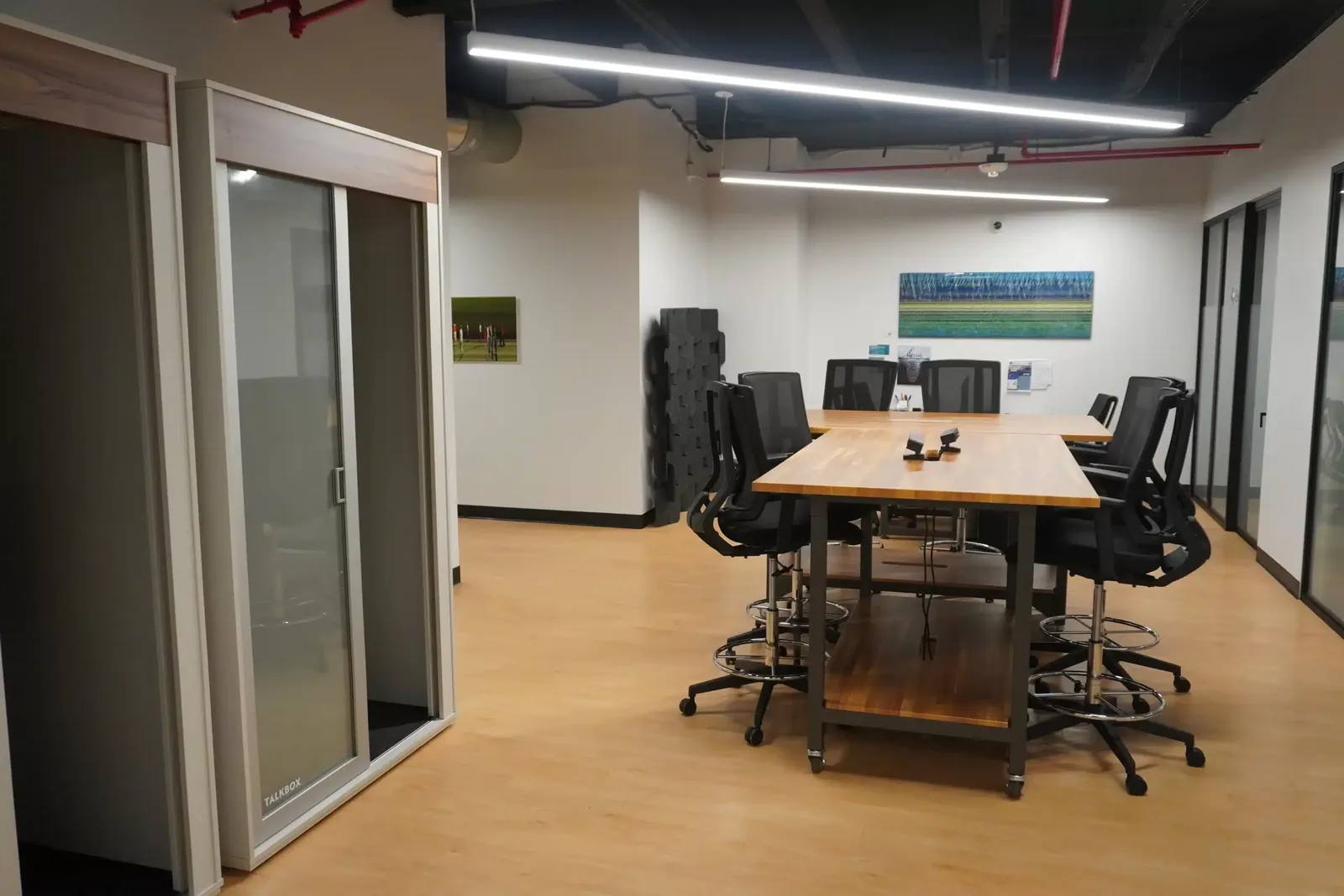 Open shared desk space at SA Cowork in San Antonio, with a communal work table and a private phone booth