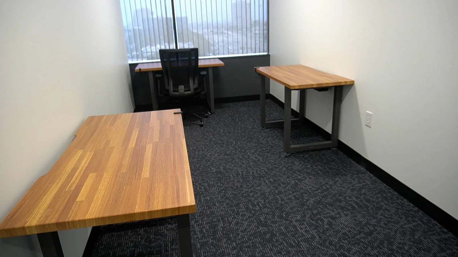 A move-in-ready private office at SA Cowork in San Antonio with desks and a window over I-10